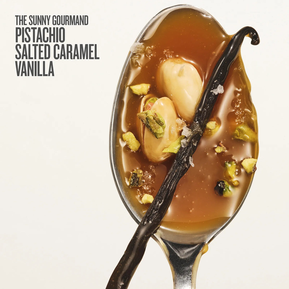 Spoon with dessert featuring salted caramel, vanilla beans, and pistachios on a white background.